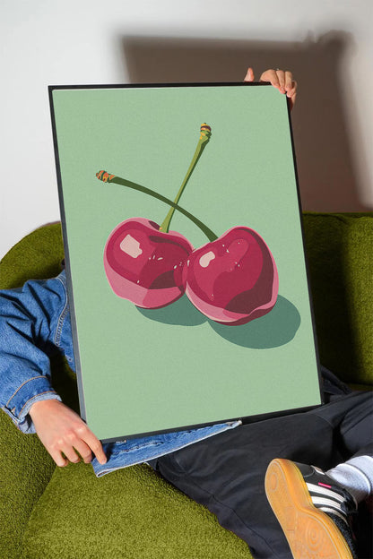 Siyah çerçeveli, açık yeşil fonda iki adet stilize pembe kiraz desenli modern poster.