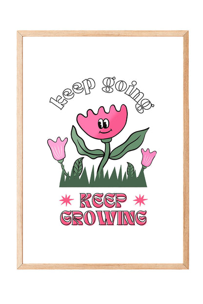 Siyah çerçeveli, beyaz zeminde pembe gülen çiçek, küçük çiçekler ve çimenler ile 'Keep Going' ve 'Keep Growing' yazılı motivasyon posteri.