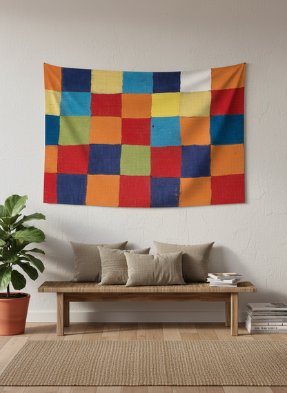 Canlı renklerde, el yapımı hissi veren kareli patchwork desenli duvar örtüsü, beyaz duvarda asılı.