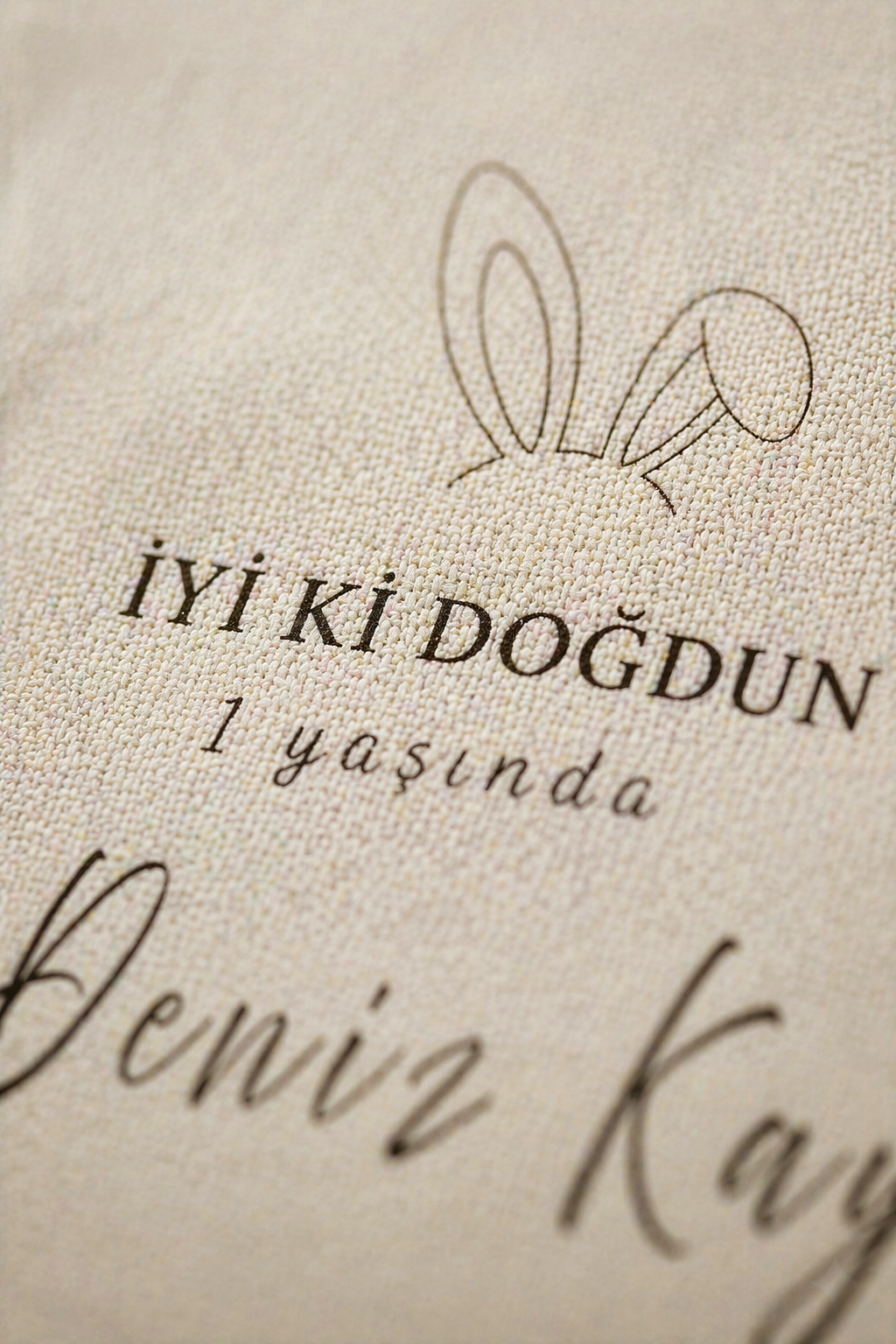 Kişiye özel bej doğum günü duvar örtüsü, tavşan kulaklı, 'İyi ki Doğdun 1 yaşında' yazılı.