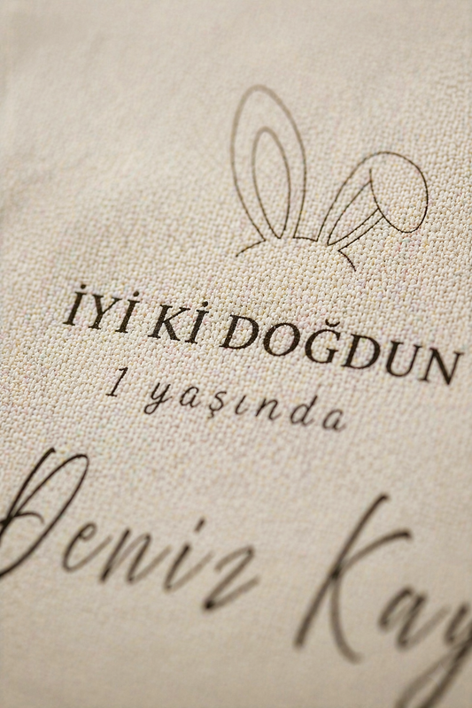 Kişiye özel bej doğum günü duvar örtüsü, tavşan kulaklı, 'İyi ki Doğdun 1 yaşında' yazılı.