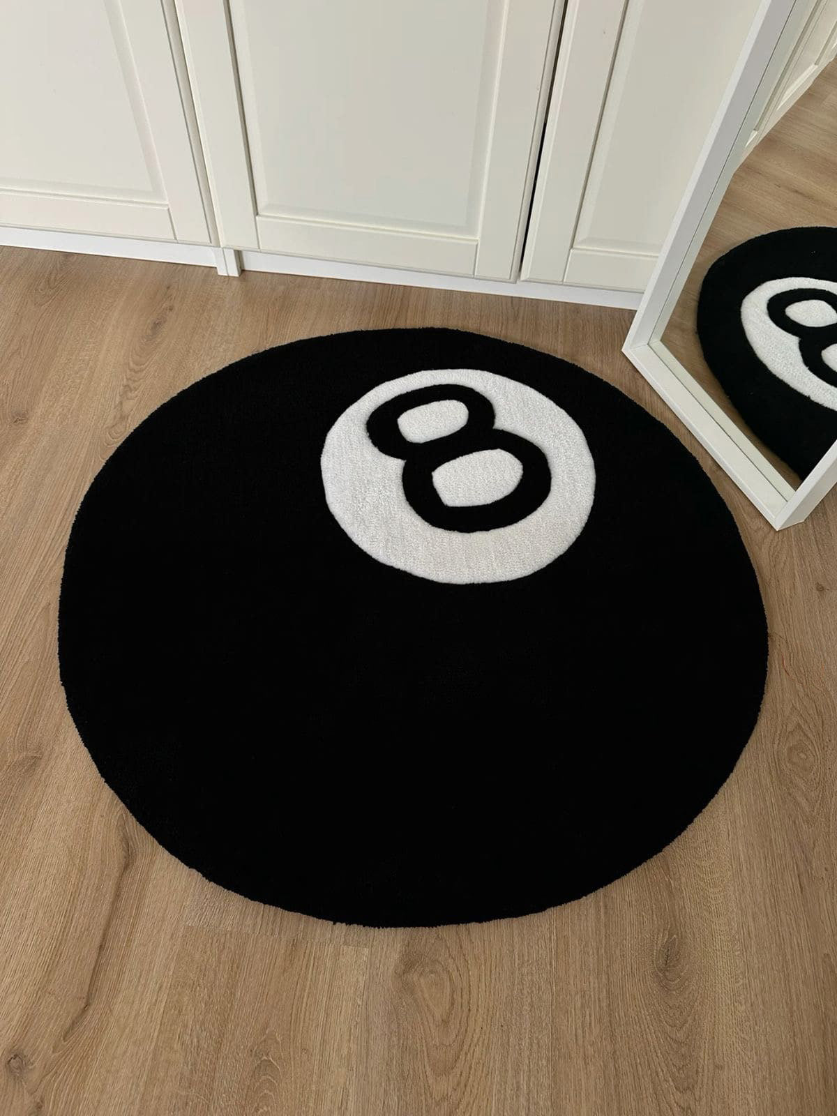 Siyah zemin üzerinde beyaz 8 rakamı bulunan, bilardo 8 topu şeklinde yuvarlak tufting halı.