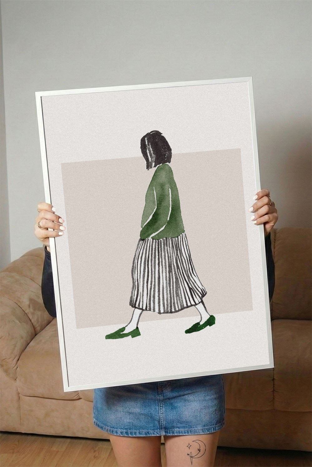Minimalist suluboya tekniğiyle yapılmış, yeşil bluzlu ve çizgili etekli yürüyen kadın figürlü çerçeveli poster