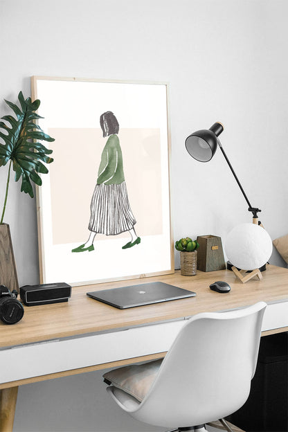 Minimalist suluboya tekniğiyle yapılmış, yeşil bluzlu ve çizgili etekli yürüyen kadın figürlü çerçeveli poster