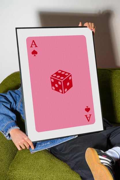Pembe zemin üzerinde maça ası iskambil kartı ve kırmızı zar figürü içeren modern çerçeveli poster