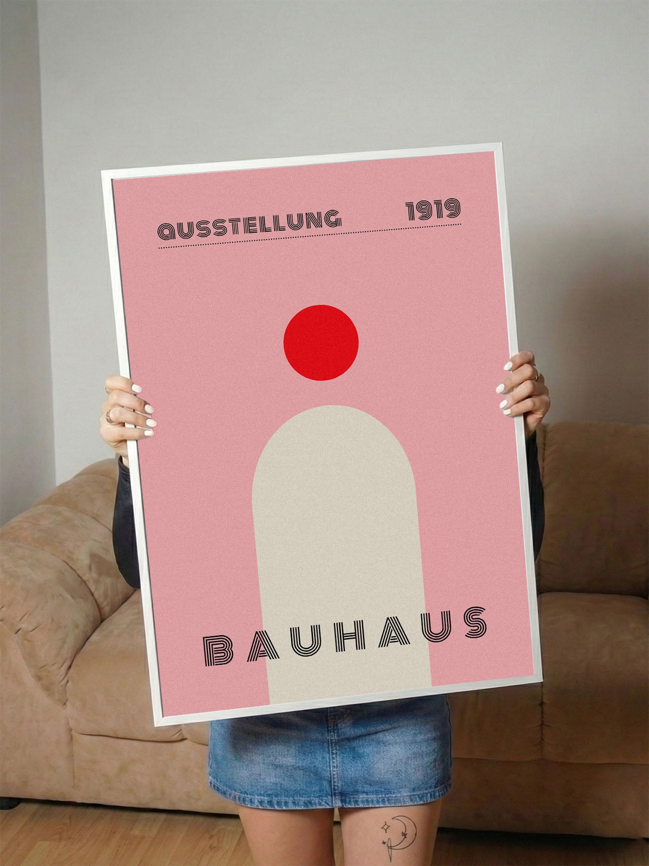 Pembe fon üzerinde kırmızı daire ve krem rengi kemer figürlü, 'Bauhaus 1919' yazılı minimalist poster.