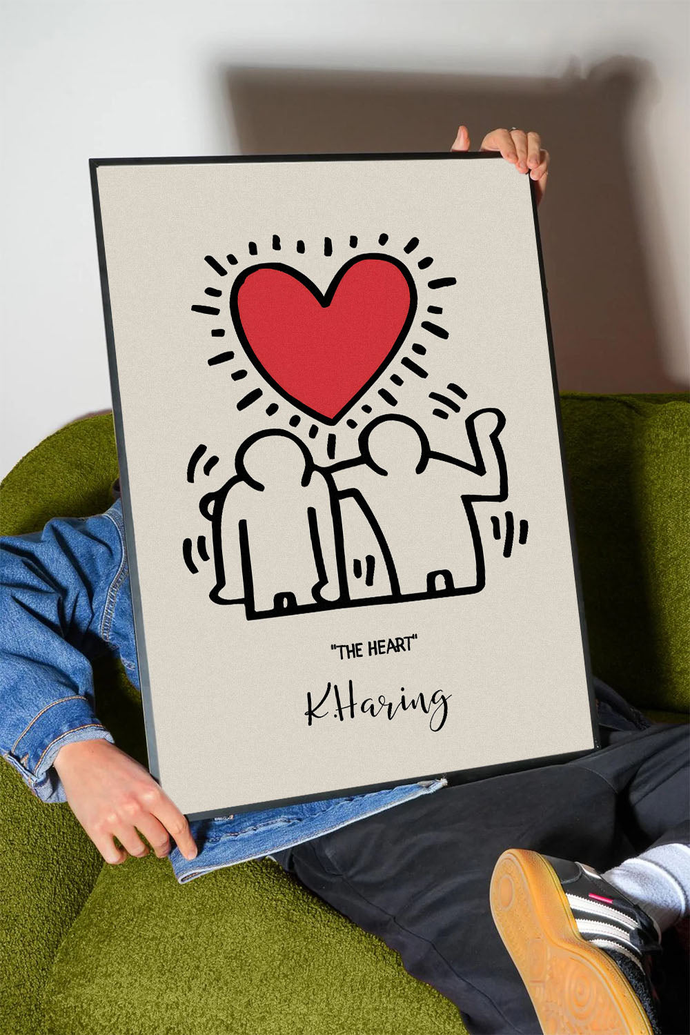 Siyah çerçeveli, bej zeminli, Keith Haring tarzı iki insan figürü ve parlak kırmızı kalp içeren modern sanat posteri.