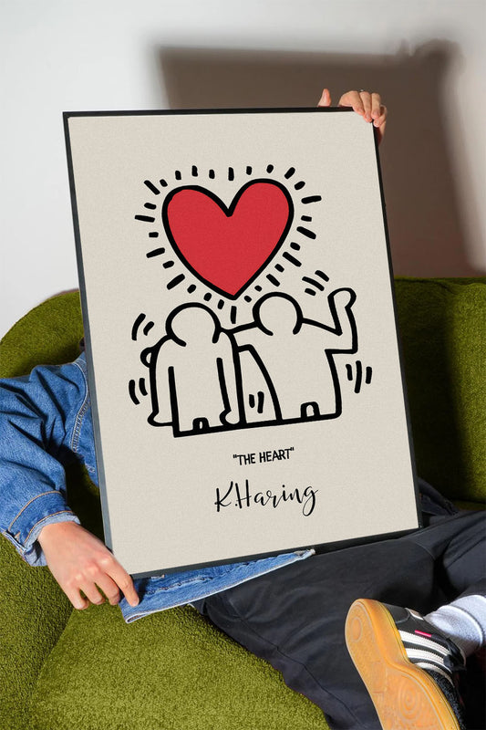Siyah çerçeveli, bej zeminli, Keith Haring tarzı iki insan figürü ve parlak kırmızı kalp içeren modern sanat posteri.