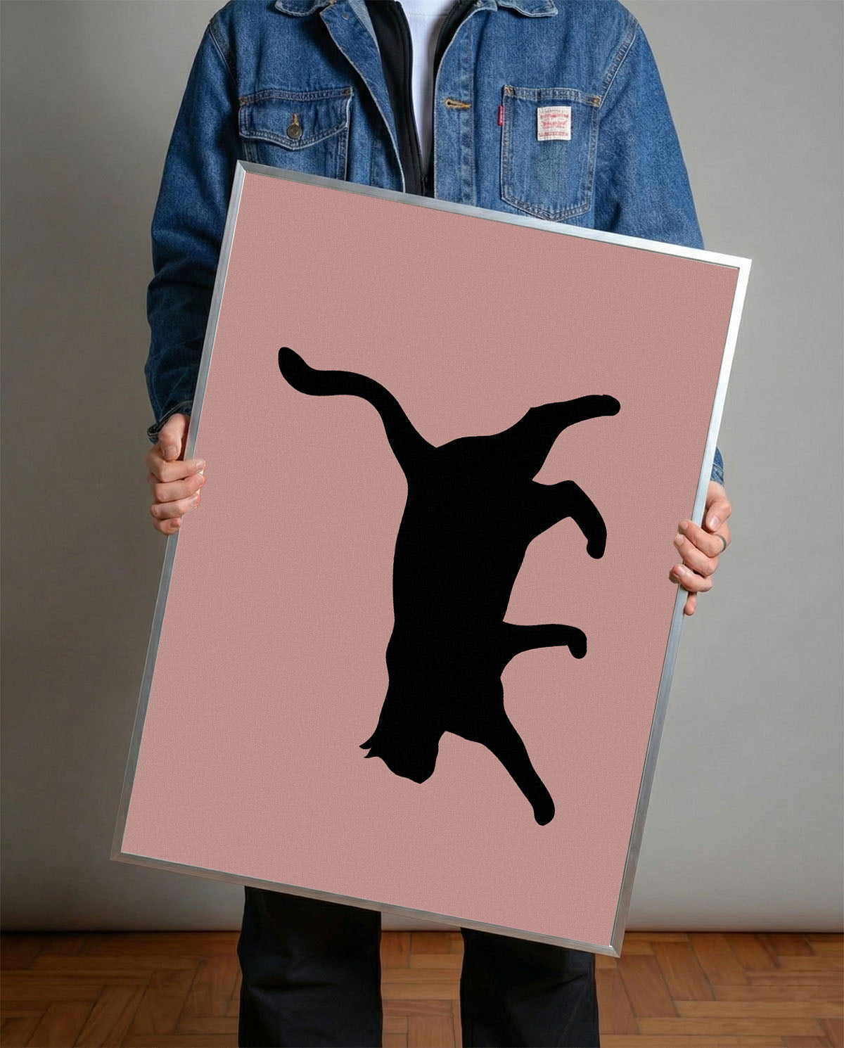 Siyah çerçeveli, pastel pembe fon üzerinde oyunbaz pozda siyah kedi silüeti minimalist poster.