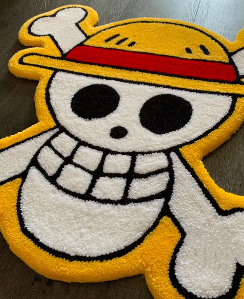 One Piece Luffy Hasır Şapka Korsan Bayrağı şeklinde el yapımı tufting halı, sarı, beyaz, siyah ve kırmızı renklerde, ahşap zeminde.