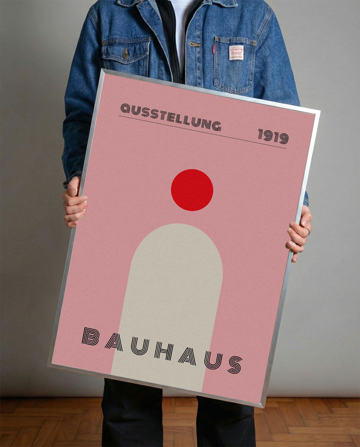 Pembe fon üzerinde kırmızı daire ve krem rengi kemer figürlü, 'Bauhaus 1919' yazılı minimalist poster.