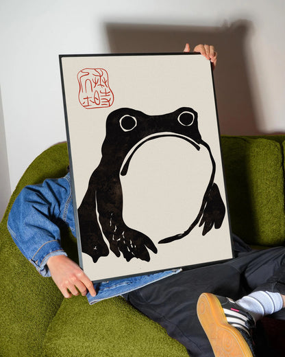 Krem rengi arka planda, dokulu siyah minimalist Japon kurbağa silüeti ve kırmızı mühürlü duvar posteri.